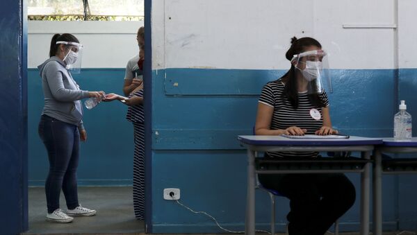 Mulher desinfeta a mão em zona eleitoral em São Bernardo do Campo, em São Paulo - Sputnik Brasil
