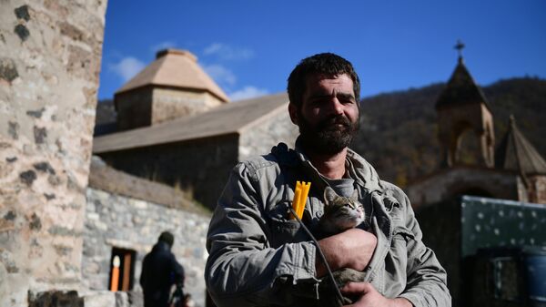 Homem segura um gato perto de um templo no mosteiro de Dadivank em Nagorno-Karabakh - Sputnik Brasil