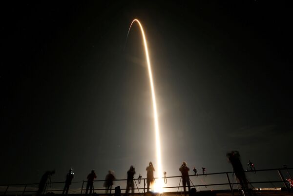 Pessoas assistem o lançamento de foguete SpaceX Falcon 9 que transporta uma cápsula Crew Dragon com quatro astronautas a bordo - Sputnik Brasil