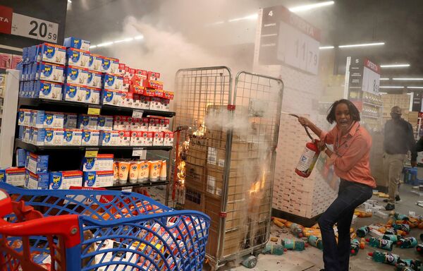 Mulher apaga fogo em loja vandalizada do supermercado Carrefour durante uma marcha em São Paulo pelo Dia da Consciência Negra e pela morte de João Alberto Silveira Freitas, homem negro que foi espancado até a morte no supermercado em Porto Alegre, 20 de novembro, 2020. - Sputnik Brasil