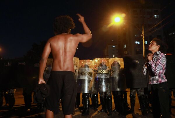 Homem negro confronta tropa de choque enquanto uma mulher negra reza durante protesto contra a morte de João Alberto Silveira Freitas, na quinta-feira (19), quando desencadeou no Brasil uma onda de indignação. - Sputnik Brasil