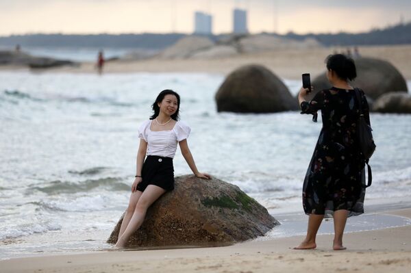 Mulher posa para foto em praia diante do Centro de Lançamento Espacial de Wenchang, no sul da China - Sputnik Brasil