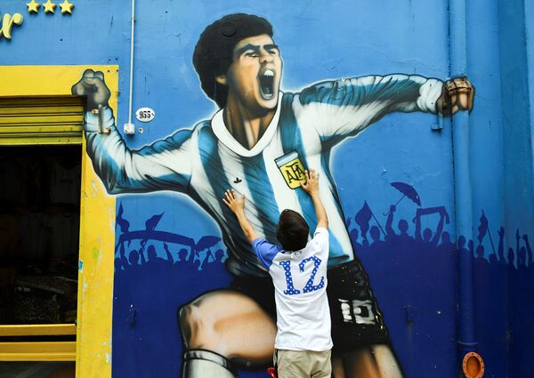 Fã lamenta a morte de Diego Maradona ao lado do seu retrato, na Argentina. - Sputnik Brasil