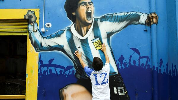Fã lamenta a morte de Diego Maradona ao lado do seu retrato, na Argentina. - Sputnik Brasil