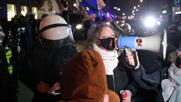 Em Varsóvia, um policial aparece atrás de Marta Lempart, liderança do movimento Strajk Kobiet (Greve das Mulheres) enquanto ela discursa durante protesto contra a proibição do aborto e em comemoração dos 102 anos do sufrágio feminino no país, em 28 de outubro de 2020 - Sputnik Brasil