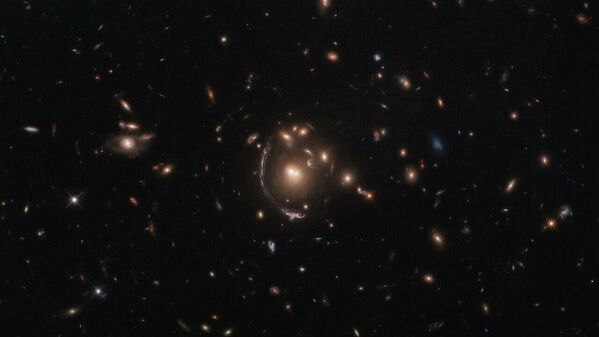 Esta imagem do telescópio espacial Hubble, da NASA e Agência Espacial Europeia, mostra a galáxia LRG-3-817, também conhecida como SDSS J090122.37+181432.3. A galáxia, cuja imagem é distorcida por efeitos da lente gravitacional, aparece como um arco longo à esquerda do grupo central de galáxias. Uma consequência importante da lente gravitacional é ampliação, permitindo-nos observar objetos que de outra forma estariam demasiado longe ou seriam demasiado fracos para ser vistos. Hubble usa este efeito de ampliação para estudar objetos para lá dos que normalmente são detectáveis com a sensibilidade de seu espelho principal de 2,4 metros de diâmetro, mostrando-nos as galáxias mais distantes que a humanidade jamais encontrou. Esta galáxia de lente gravitacional foi encontrada como parte da Pesquisa de Arcos Brilhantes de Sloan, que descobriu algumas de galáxias de lentes gravitacionais mais brilhantes com alto desvio para o vermelho no céu noturno - Sputnik Brasil