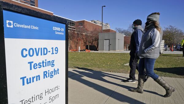 Duas pessoas passam perto da placa informativa sobre testes de COVID-19 na Clínica de Cleveland, no estado americano do Ohio - Sputnik Brasil
