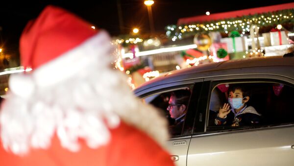 Criança acena para uma pessoa vestida de Papai Noel na cidade Juarez, no México - Sputnik Brasil