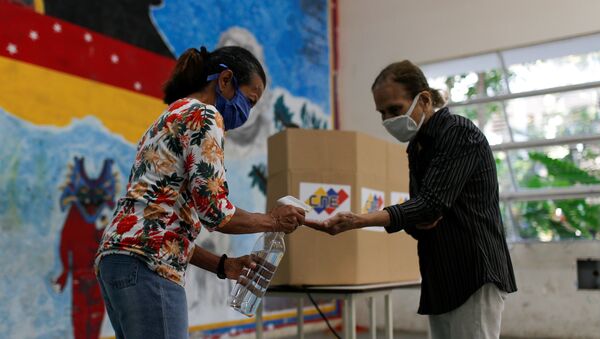Eleitores higienizam as mãos em zona eleitoral em Caracas - Sputnik Brasil
