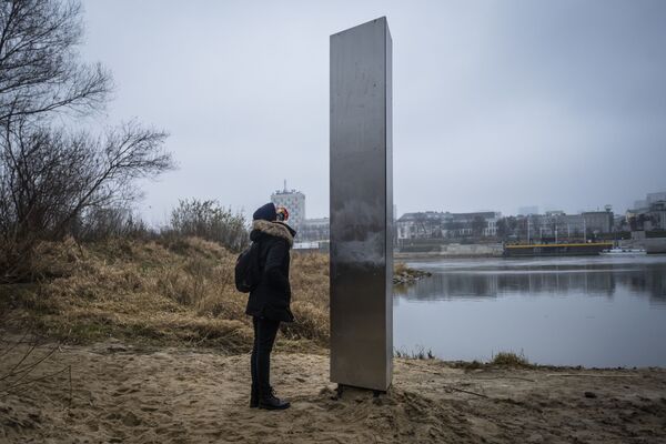 Mulher ao pé do monólito metálico que surgiu nas margens do rio Vístula, em Varsóvia, Polônia
 - Sputnik Brasil