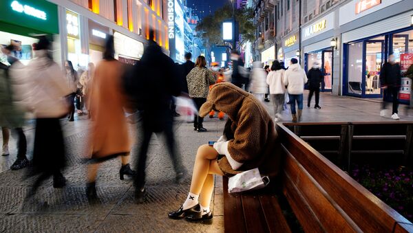Moça com celular no principal bairro comercial da cidade de Wuhan, China, um ano após o início da pandemia - Sputnik Brasil