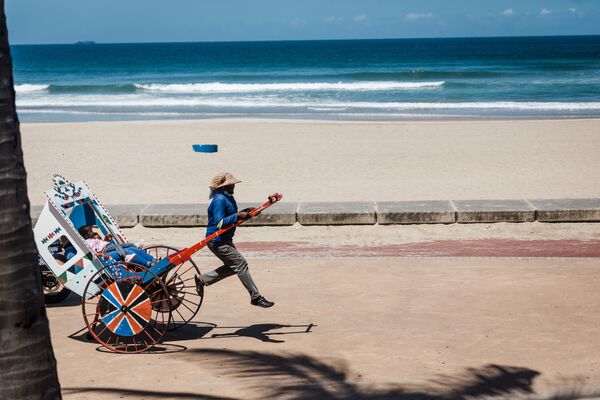 Puxador de riquixá se ocupa de seu negócio com turistas na praia North Beach, Durban, África do Sul, depois de restrições impostas pelo governo proibirem as pessoas de nadarem na costa devido à segunda onda da COVID-19, 16 de dezembro de 2020 - Sputnik Brasil