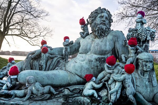 Estatuetas de bronze na estátua de Nilen em Copenhague, Dinamarca, usando gorros vermelhos e pequenas máscaras, 16 de dezembro de 2020 - Sputnik Brasil