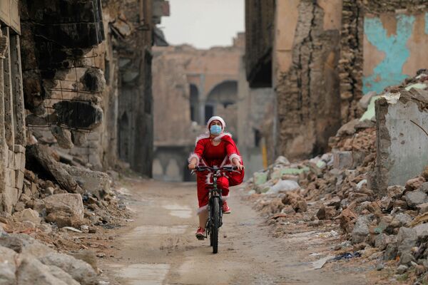 Mulher iraquiana vestida de Papai Noel anda de bicicleta em Mosul, Iraque, 18 de dezembro de 2020 - Sputnik Brasil