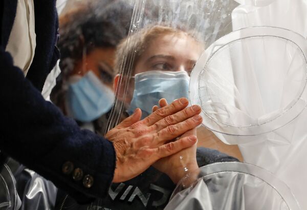 Menino hospitalizado infectado com COVID-19 toca a mão de seu pai através de proteção de plástico no hospital de San Raffaele em Roma, Itália, 22 de dezembro de 2020 - Sputnik Brasil