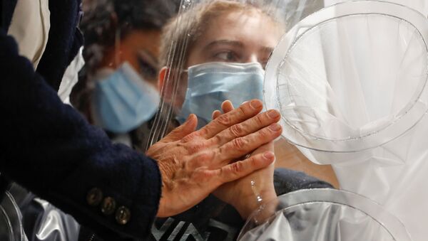 Menino hospitalizado infectado com COVID-19 toca a mão de seu pai através de proteção de plástico no hospital de San Raffaele em Roma, Itália, 22 de dezembro de 2020 - Sputnik Brasil