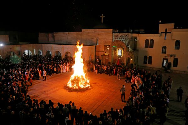 Cristãos iraquianos se reúnem em torno de fogueira durante missa de Natal em Hemdaniye, Iraque, 24 de dezembro de 2020 - Sputnik Brasil