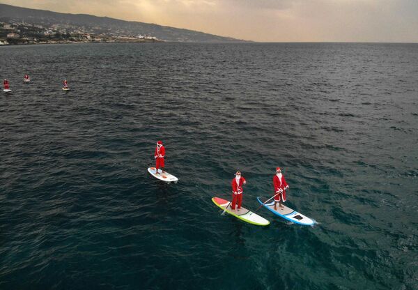 Libaneses vestidos de Papai Noel praticam surfe com remo na cidade de Batroun, Líbano, 22 de dezembro de 2020 - Sputnik Brasil