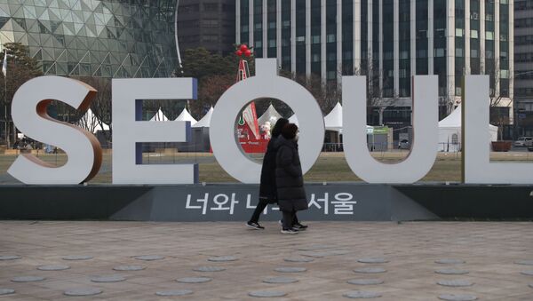 Mulheres usando máscaras faciais como precaução contra o coronavírus caminham perto da exibição do logotipo da capital da Coreia do Sul, Seul - Sputnik Brasil