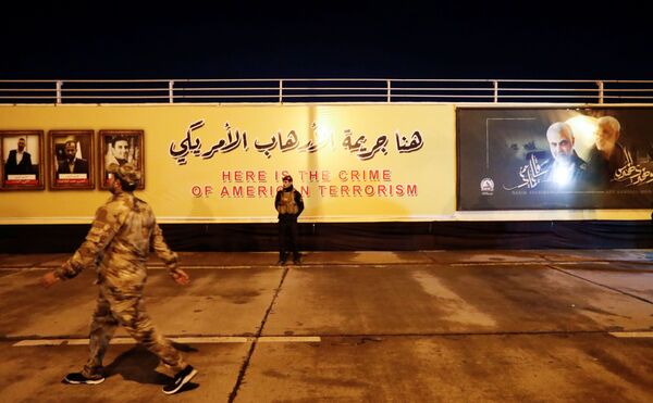 Combatente das Forças de Mobilização Popular xiitas do Iraque fica em pé tendo ao fundo imagens do major-general iraniano Qassem Soleimani e do líder da milícia xiita iraquiana Abu Mahdi al-Muhandis - Sputnik Brasil