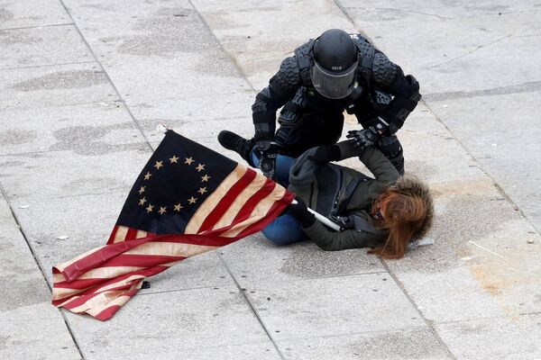 Policial detém uma manifestante pró-Trump durante o protesto contra a certificação dos resultados das eleições presidenciais de 2020 pelo Congresso dos Estados Unidos, em Washington, Estados Unidos, 6 de janeiro de 2021 - Sputnik Brasil