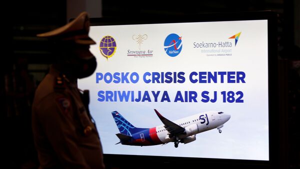 Policial passa em frente ao monitor do comitê de crise temporário instalado após o avião da Sriwijaya Air cair na Indonésia. - Sputnik Brasil