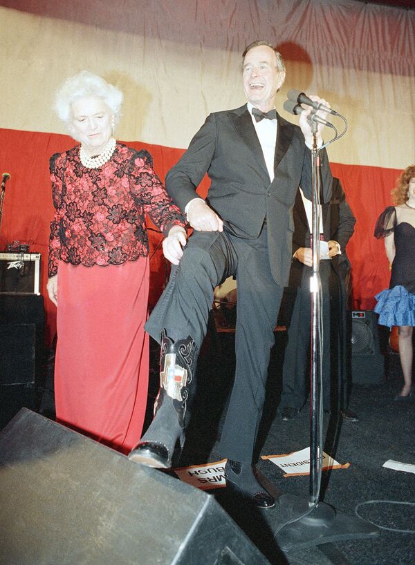 Primeira-dama Barbara Bush ajuda seu marido, o presidente George H. Bush, a mostrar uma bota com emblema do estado do Texas durante uma recepção com gravata preta e botas do Texas em Washington, Estados Unidos, 21 de janeiro de 1989 - Sputnik Brasil