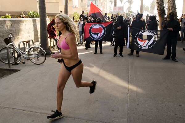 Mulher corre frente a contramanifestantes, alguns carregando bandeiras de Antifa, esperando confrontar a manifestação dos apoiadores do presidente Donald Trump, San Diego, Califórnia, EUA, 9 de janeiro de 2021 - Sputnik Brasil