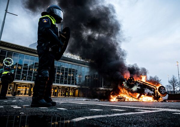 Carro em chamas em frente da estação ferroviária, 24 de janeiro de 2021, após protestos contra a política do coronavírus, em Eindhoven, Países Baixos, 24 de janeiro de 2021 - Sputnik Brasil
