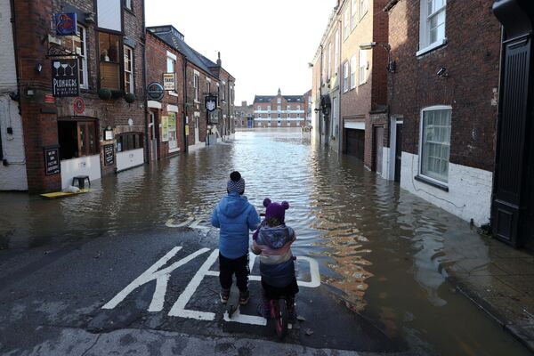 Duas crianças em rua parcialmente inundada após o rio Ouse transbordar, no Reino Unido, 22 de janeiro de 2021 - Sputnik Brasil