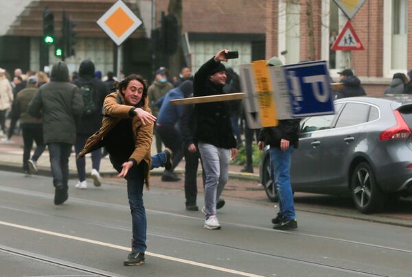 Manifestante joga placa de rua durante protesto contra restrições para conter a propagação do coronavírus, Amsterdã, Países Baixos, 24 de janeiro de 2021 - Sputnik Brasil