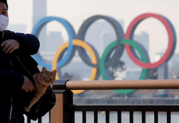 Homem com gato no saco em frente aos anéis olímpicos, Tóquio, Japão, 22 de janeiro de 2021 - Sputnik Brasil