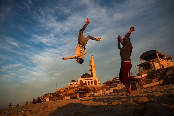 Crianças palestinas praticam parkour ao longo de uma praia na cidade de Gaza, Palestina, ao pôr do sol, em 27 de janeiro de 2021 - Sputnik Brasil