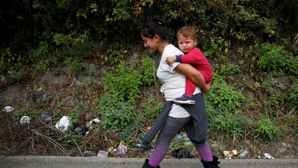 A Honduran woman carries a child as she takes part in a new caravan of migrants, set to head to the United States, in Chiquimula, Guatemala January 16, 2021 - Sputnik Brasil