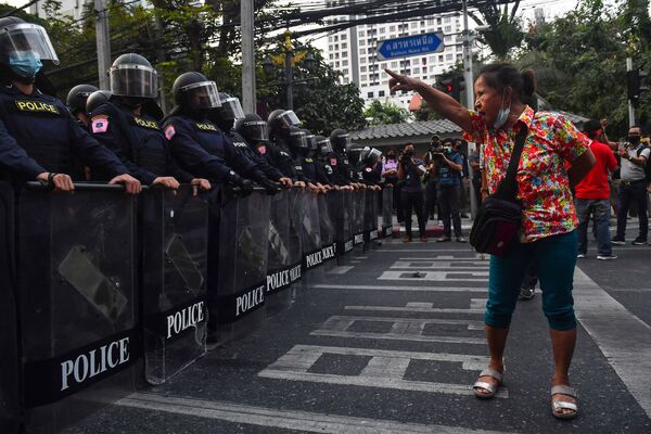 Manifestante em Bangkok, Tailândia, mostra gestos à polícia de choque, em 1º de fevereiro de 2021, perto de migrantes de Mianmar protestando após o golpe militar em seu país - Sputnik Brasil