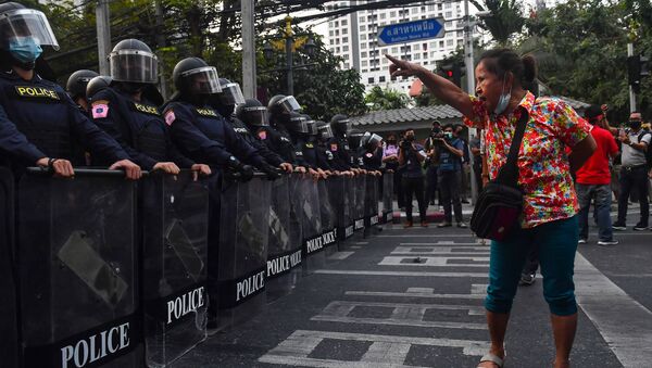 Manifestante em Bangkok, Tailândia, mostra gestos à polícia de choque, em 1º de fevereiro de 2021, perto de migrantes de Mianmar protestando após o golpe militar em seu país - Sputnik Brasil