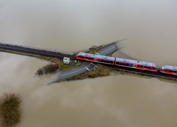 Trem passa cruzamento de ferrovia rodeado por água devido a inundação causada pela chuva e degelo, Alemanha, 3 de fevereiro de 2021 - Sputnik Brasil