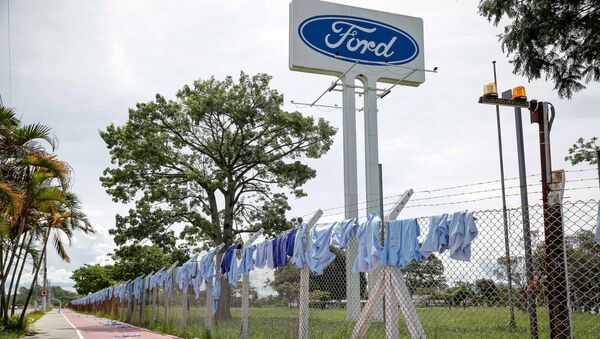 Trabalhadores da Ford em Taubaté realizaram um protesto na portaria principal da fábrica. Eles colocaram uniformes pendurados nas grades da empresa e anotaram em cada camisa o nome das famílias que serão afetadas pelo fechamento da montadora. - Sputnik Brasil