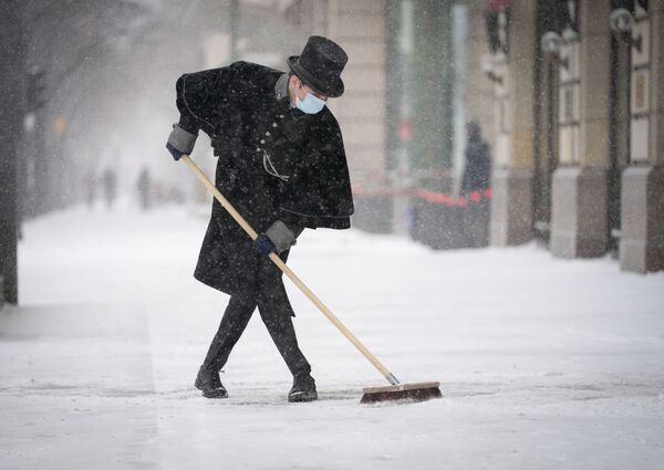 Empregado do Hotel Adlon limpa a calçada da neve em Berlim, Alemanha, em 8 de fevereiro de 2021 - Sputnik Brasil