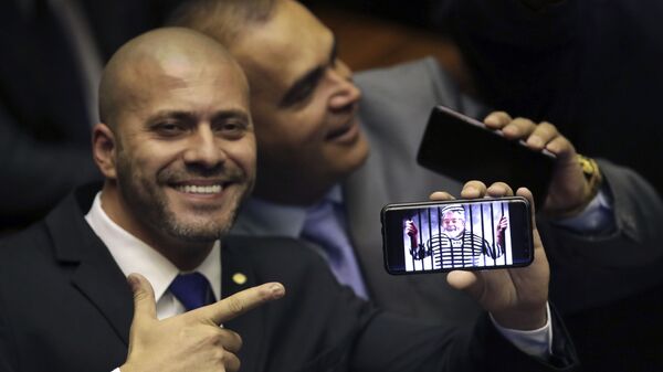 O deputado federal Daniel Silveira (PSL-RJ) segura imagem no celular com uma montagem do ex-presidente Luiz Inácio Lula da Silva preso em sessão da Câmara dos Deputados. - Sputnik Brasil