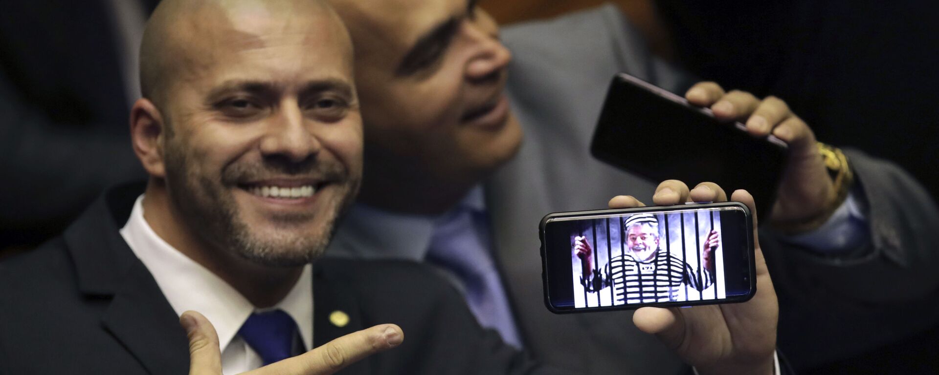 O deputado federal Daniel Silveira (PSL-RJ) segura imagem no celular com uma montagem do ex-presidente Luiz Inácio Lula da Silva preso em sessão da Câmara dos Deputados. - Sputnik Brasil, 1920, 28.04.2021