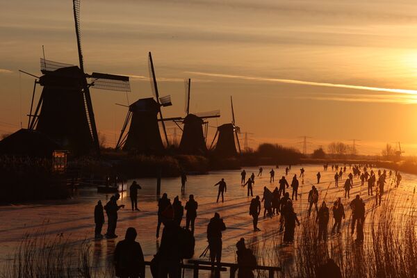 Patinadores deslizam no gelo perto de moinhos de vento no povoado de Kinderdijk, Países Baixos, 14 de fevereiro de 2021 - Sputnik Brasil