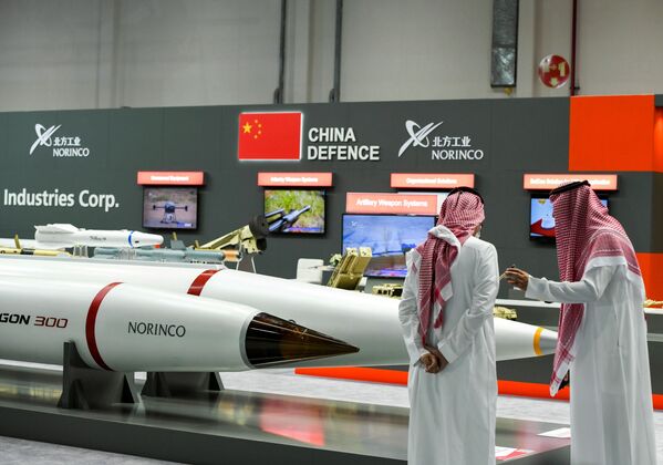 Homens ao lado de produtos em exposição na IDEX 2021 em Abu Dhabi, EAU, 21 de fevereiro de 2021 - Sputnik Brasil