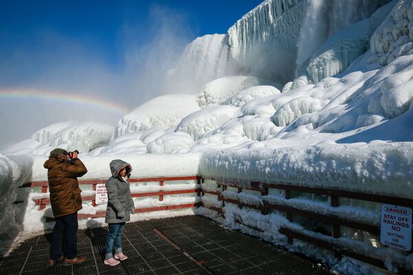 Visitantes em meio ao arco-íris sobre o gelo na base das cataratas do Niágara, Nova York, EUA, 21 de fevereiro de 2021 - Sputnik Brasil