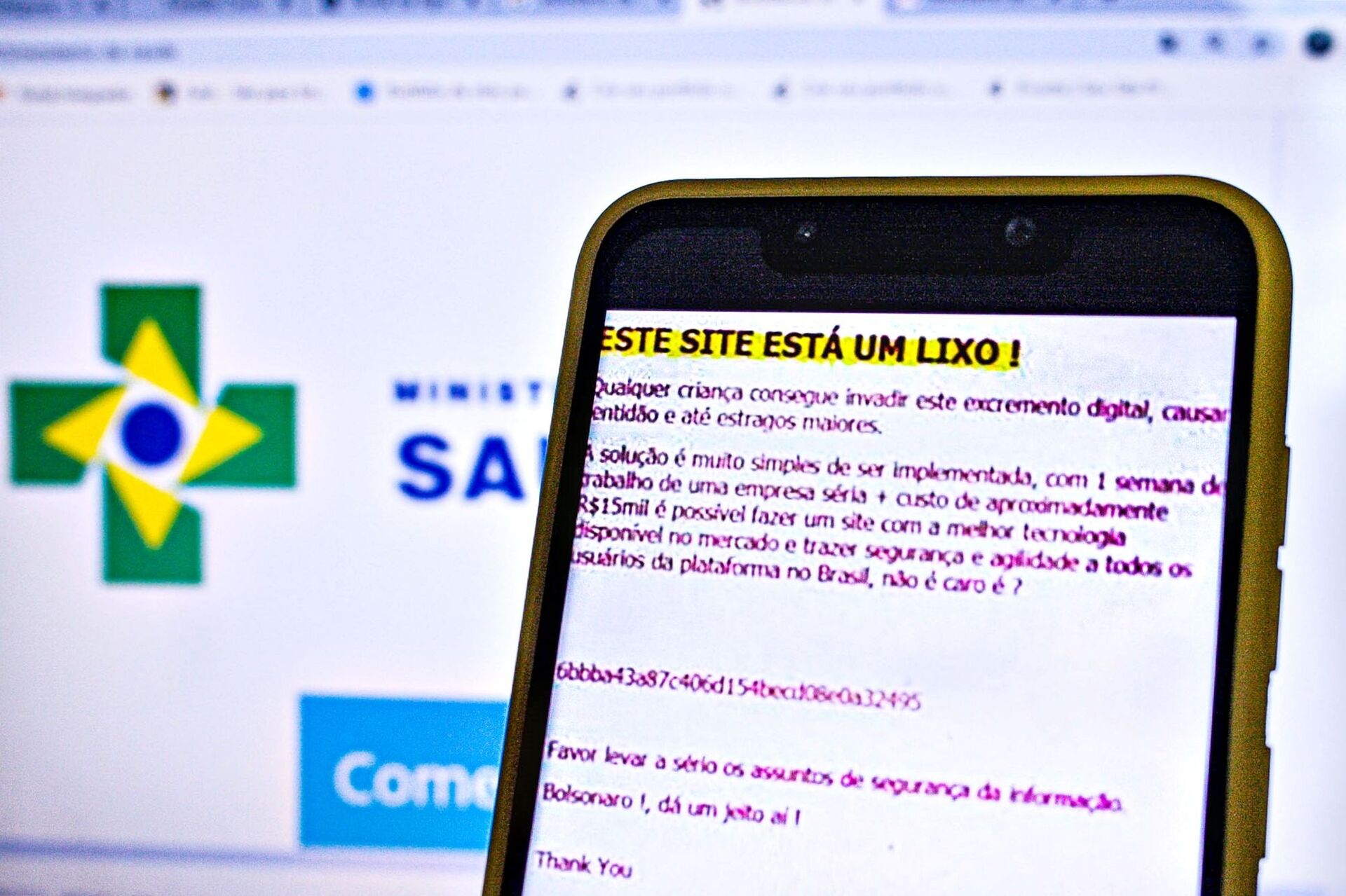 Um smartphone mostra uma mensagem deixada por um hacker em ataque ao site do Ministério da Saúde, mostrado no fundo. - Sputnik Brasil, 1920, 10.12.2021