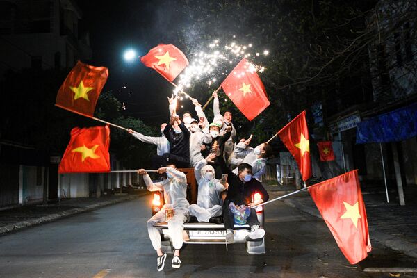 Residentes saindo às ruas para celebrar com bandeiras nacionais e fogos de artifício após o cancelamento do distanciamento social na cidade Chi Linh, Vietnã, 3 de março de 2021 - Sputnik Brasil