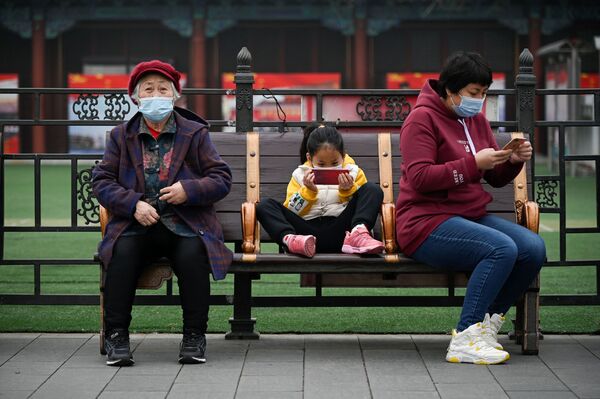 Menina usa celular enquanto descansa em um banco em Pequim, China, 4 de março de 2021 - Sputnik Brasil