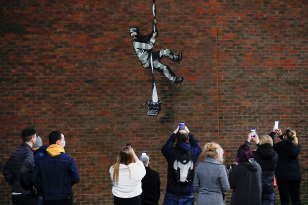 Pessoas tirando fotos perto de novo grafite em um muro, feito alegadamente por Banksy, Reino Unido, 1º de março de 2021 - Sputnik Brasil