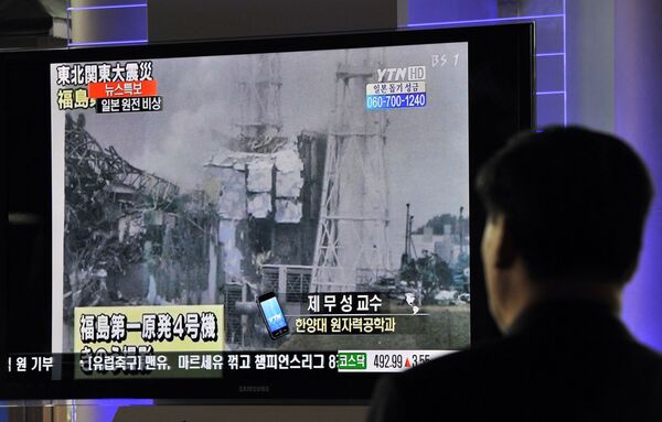 Passageiros sul-coreanos passam por noticiários sobre a explosão e colapso na usina nuclear japonesa de Fukushima Daiichi na estação ferroviária em Seul, 16 de março de 2011 - Sputnik Brasil