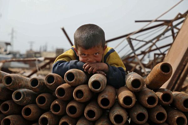 Criança debruçada sobre monte de projéteis desativados na cidade de Maaret Misrin, Síria
 - Sputnik Brasil